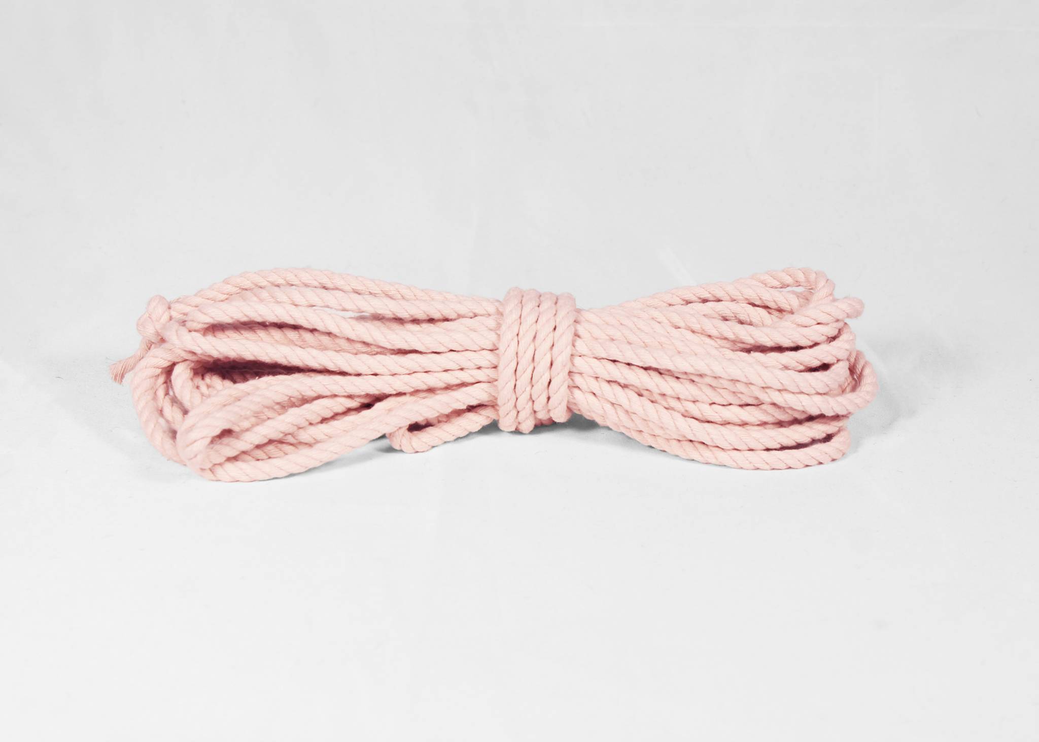A coiled bundle of light pink braided rope, tied in the center, displayed on a clean white background.